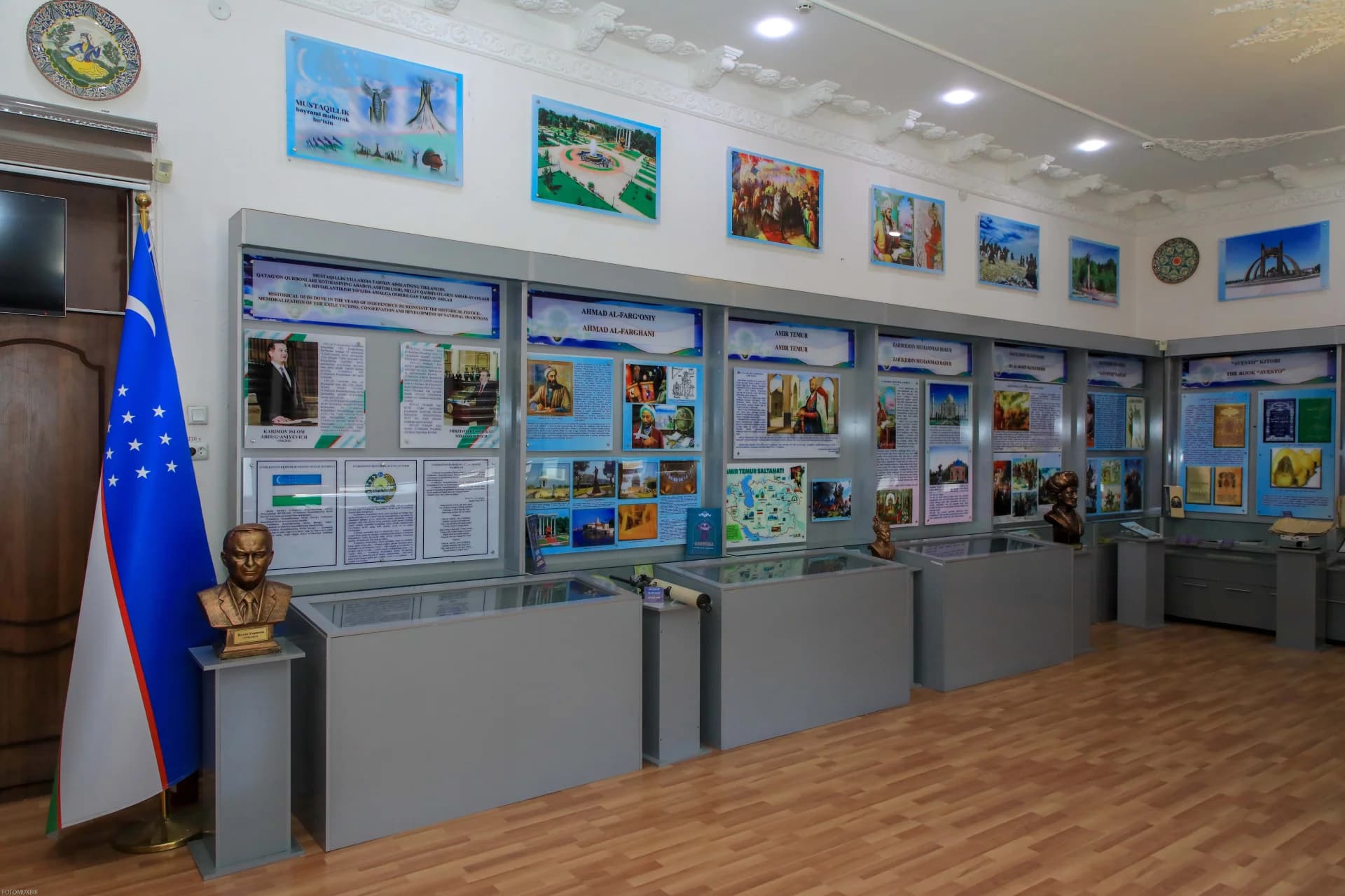 Interior view of an exhibition space featuring informational displays, photographs, busts, and a national flag
