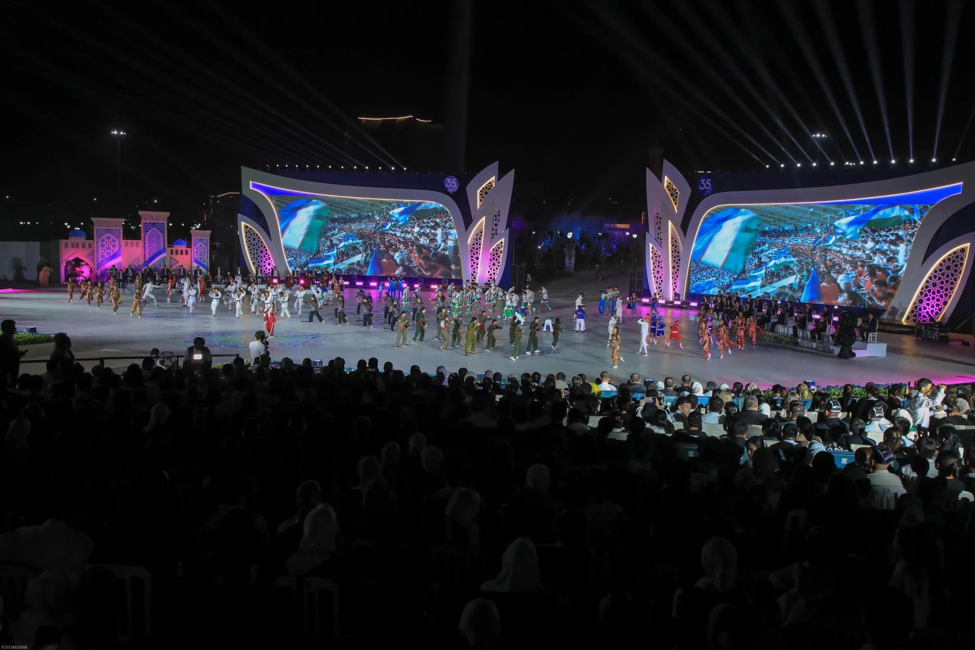 Performers on stage during an evening event before a large audience