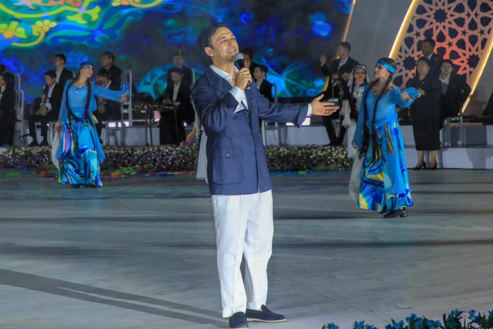 Man singing on stage with performers