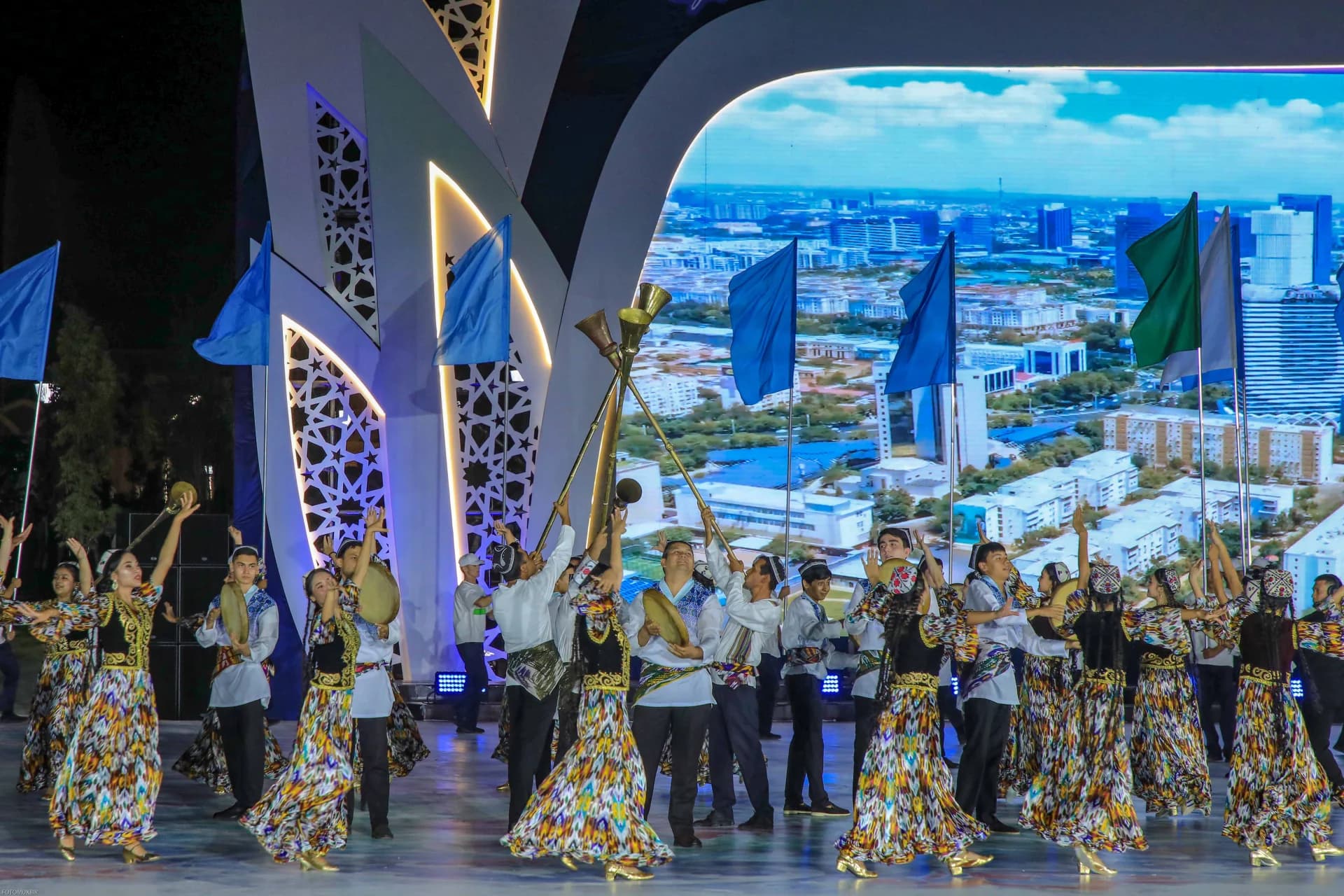 Performers in traditional attire holding flags on stage