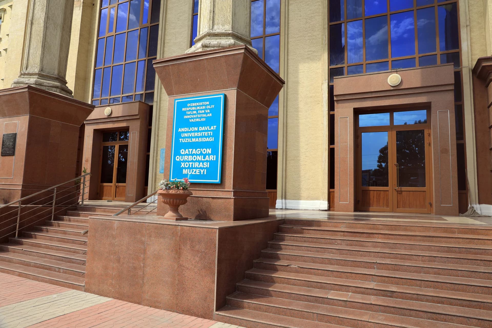 Building facade with entrance stairs and a blue information sign