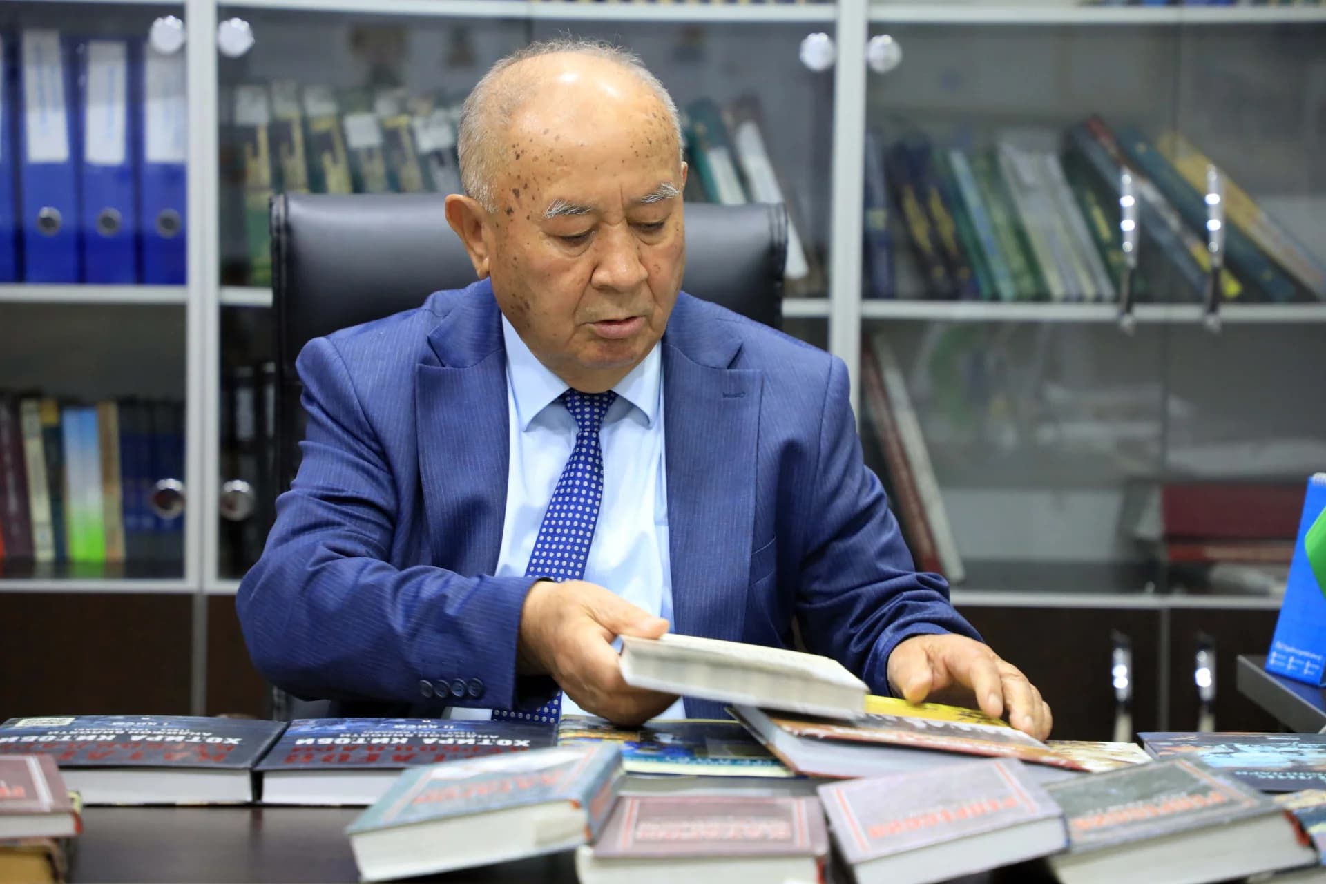 Man looking at books at a desk indoors
