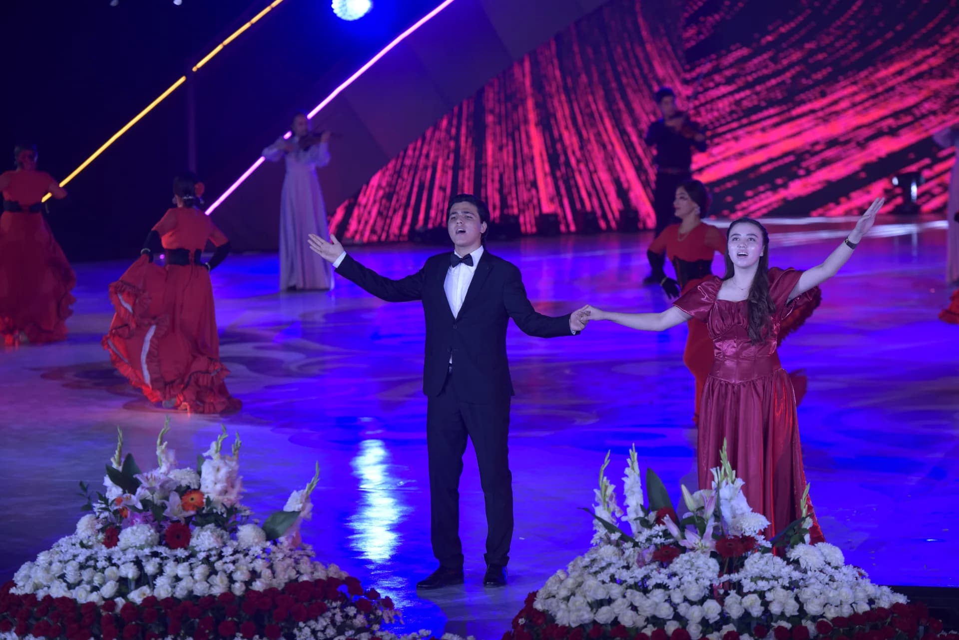 Performers singing on a brightly lit stage during a concert event