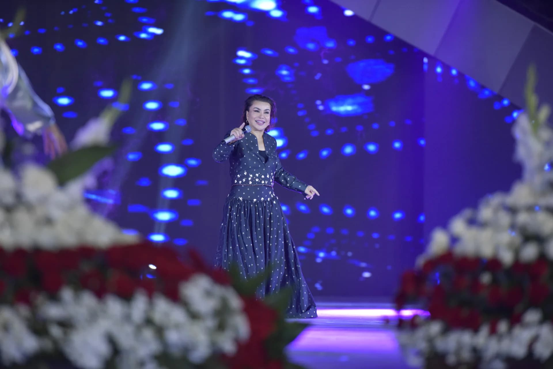 A woman performing on stage with blue background lights