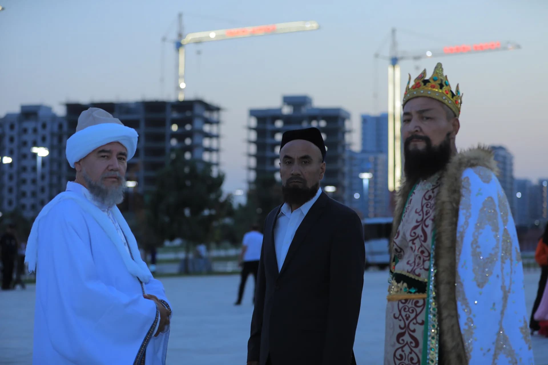 Three men in traditional and modern attire standing outdoors