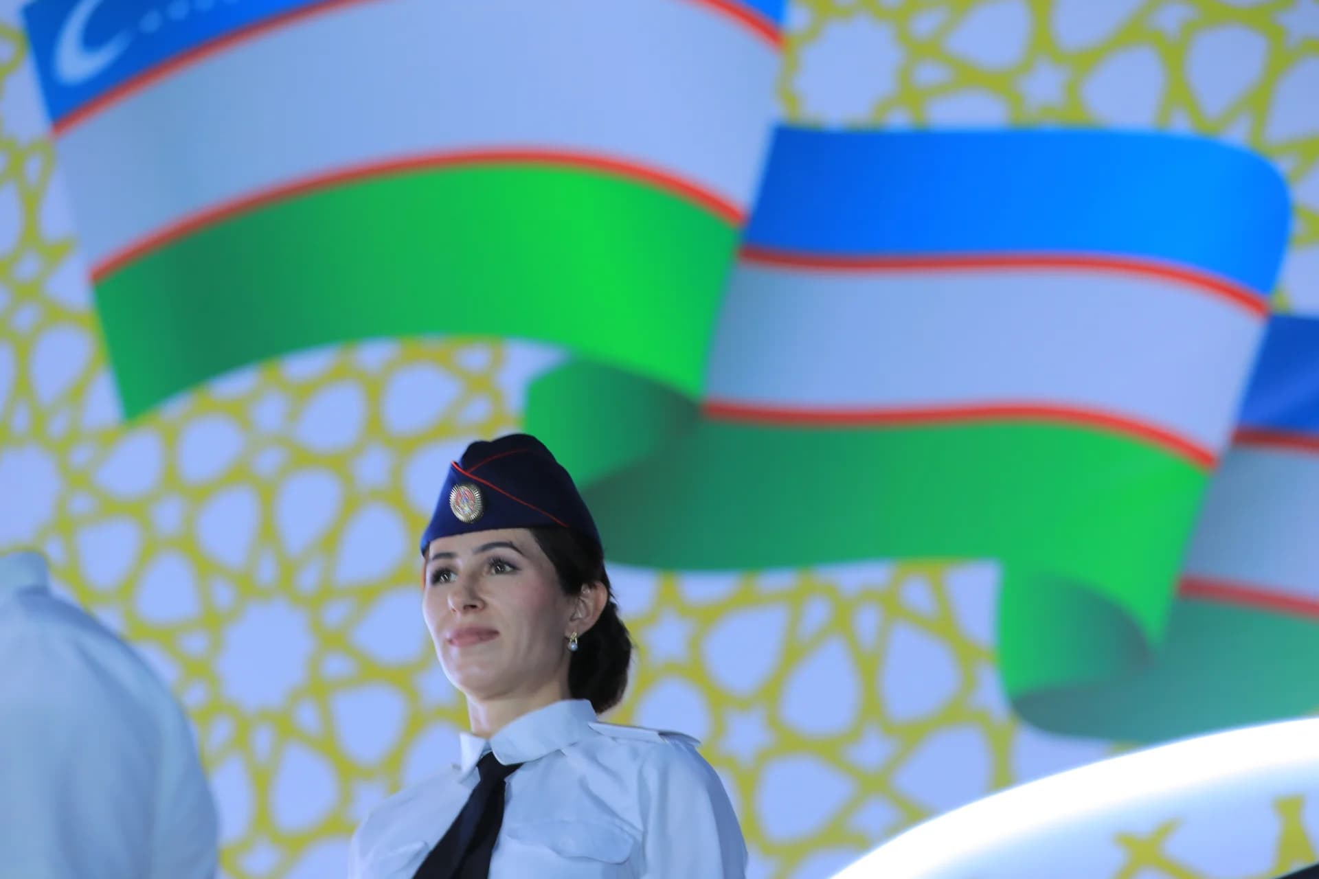 Person in uniform standing in front of flags
