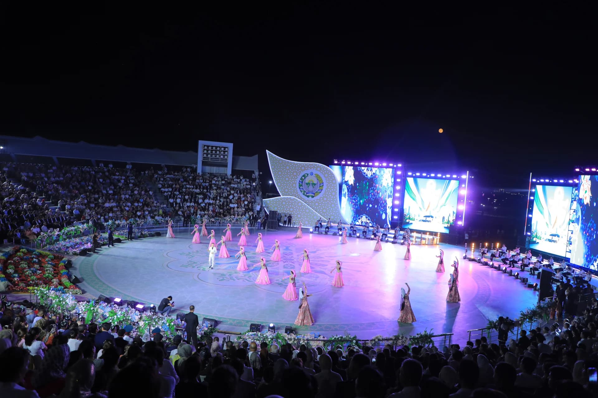 Performers on a lit stage during an outdoor evening event