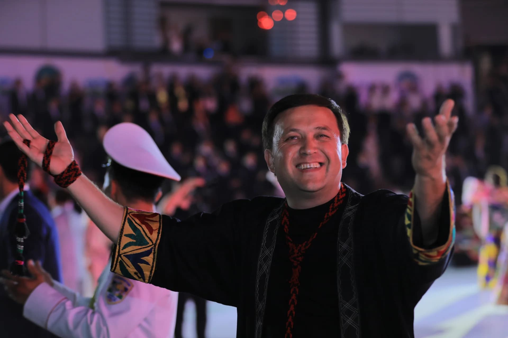 Smiling man in traditional attire gesturing with open hands