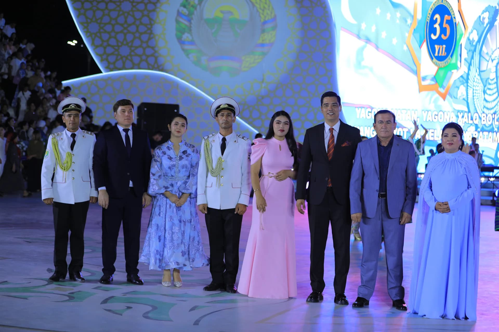 Group portrait of people in formal and military attire standing on stage