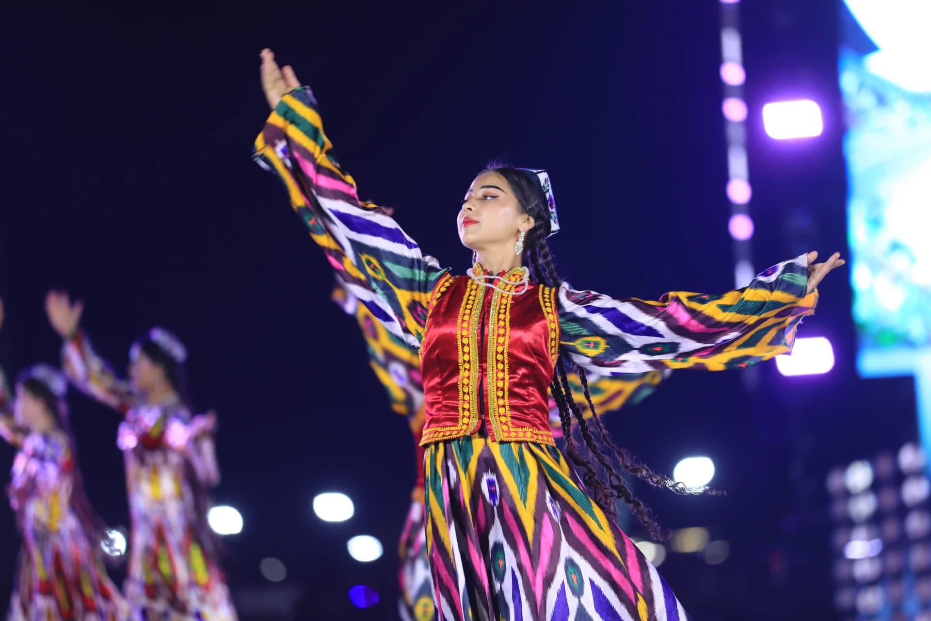 Performer in traditional attire dancing outdoors at night