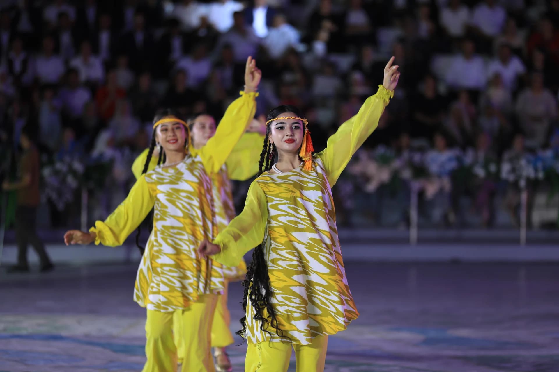 Performers in matching yellow attire dancing during a cultural program