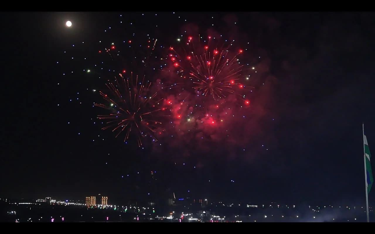 Bright fireworks lighting up the night sky over a city skyline