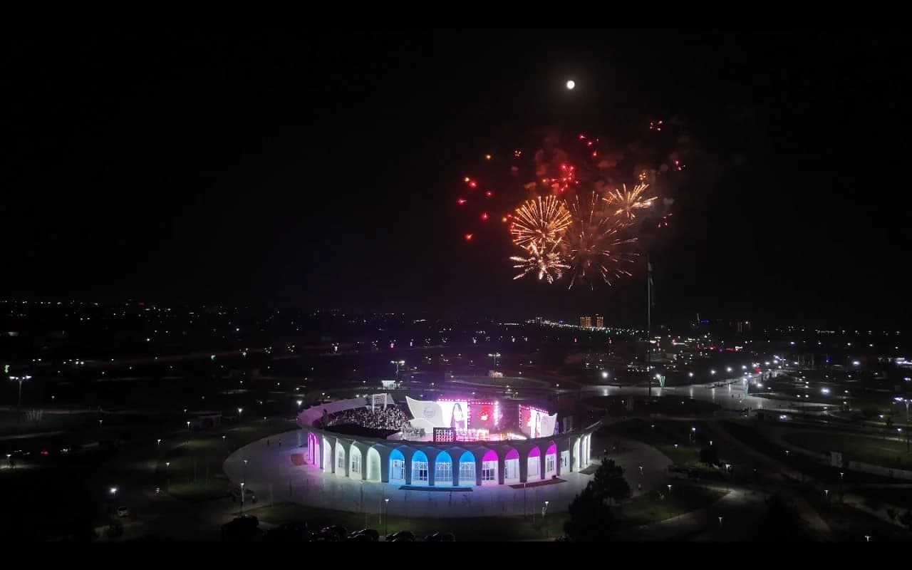 Fireworks display over an illuminated amphitheater at night