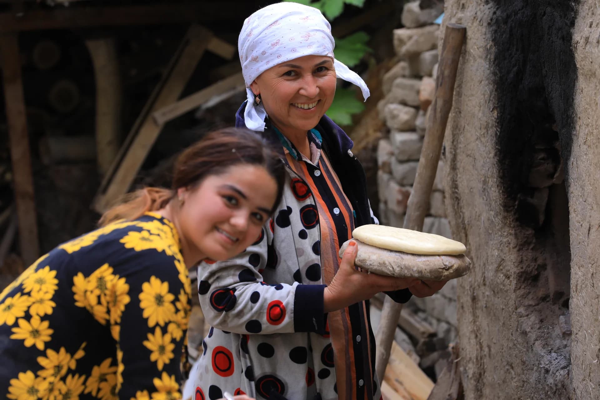 People baking traditional bread near an outdoor clay oven