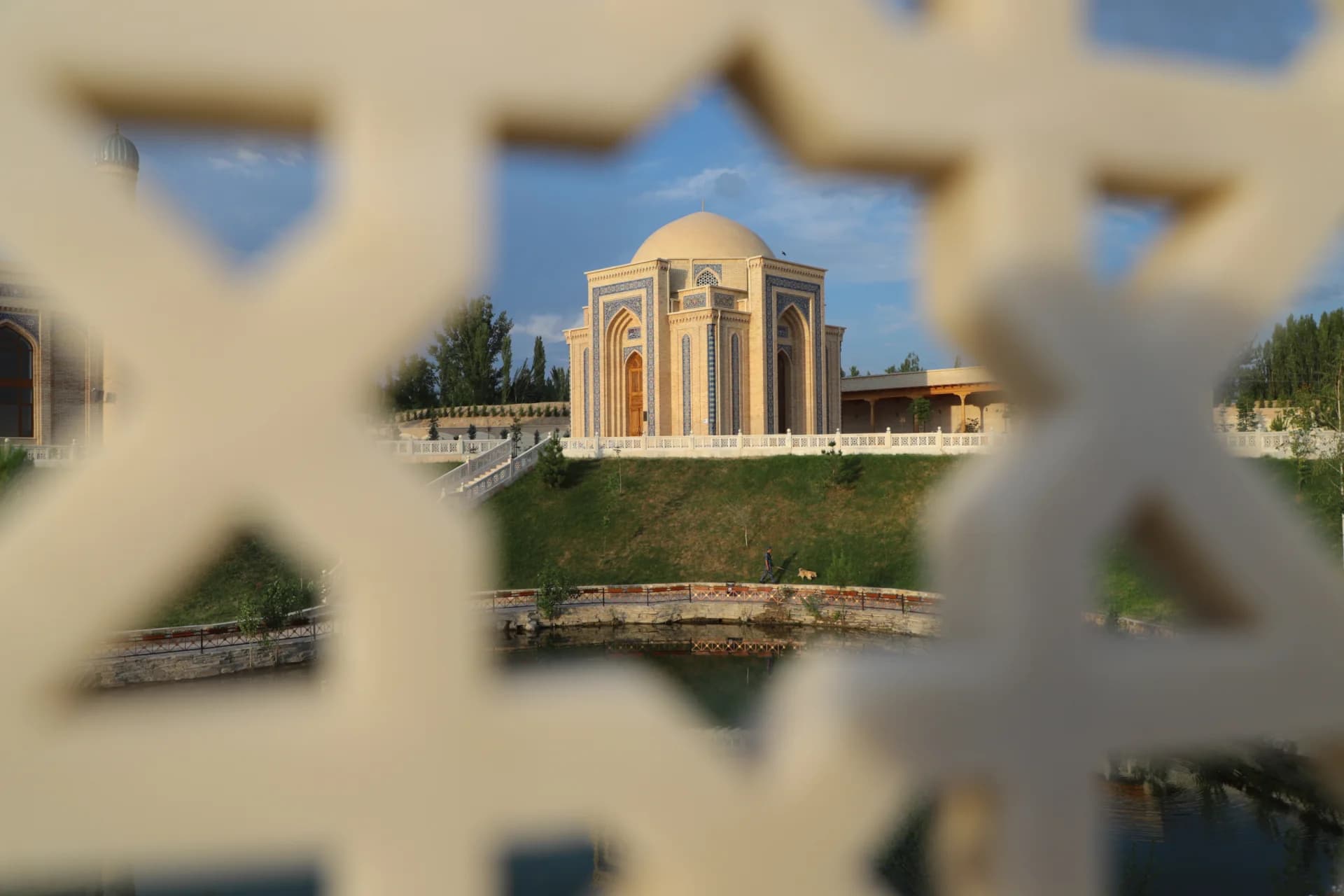 View of a domed mausoleum seen through an ornamental architectural screen