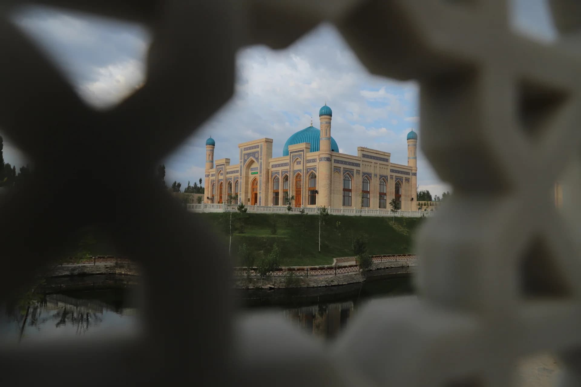 Historic mosque building with blue domes viewed through decorative architectural lattice