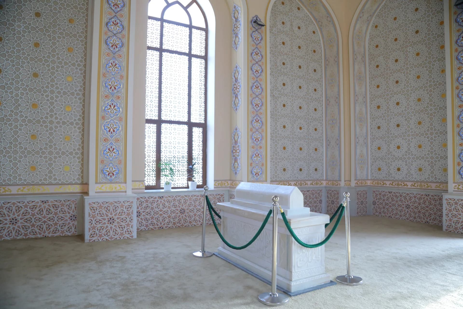 Interior view of an ornate hall with a white marble tomb enclosure