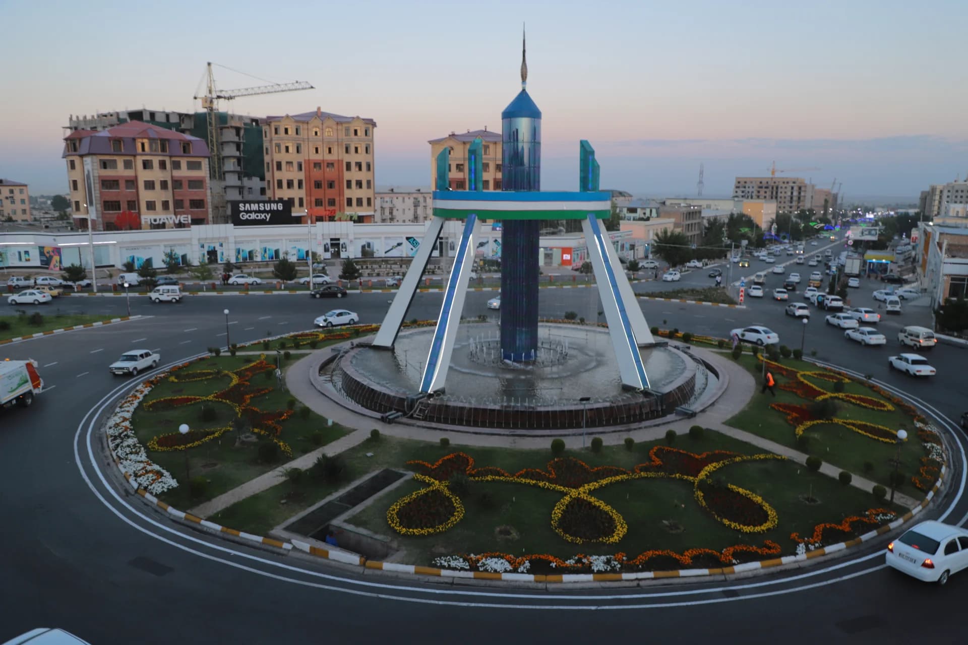 City roundabout with a central monument and fountain surrounded by traffic