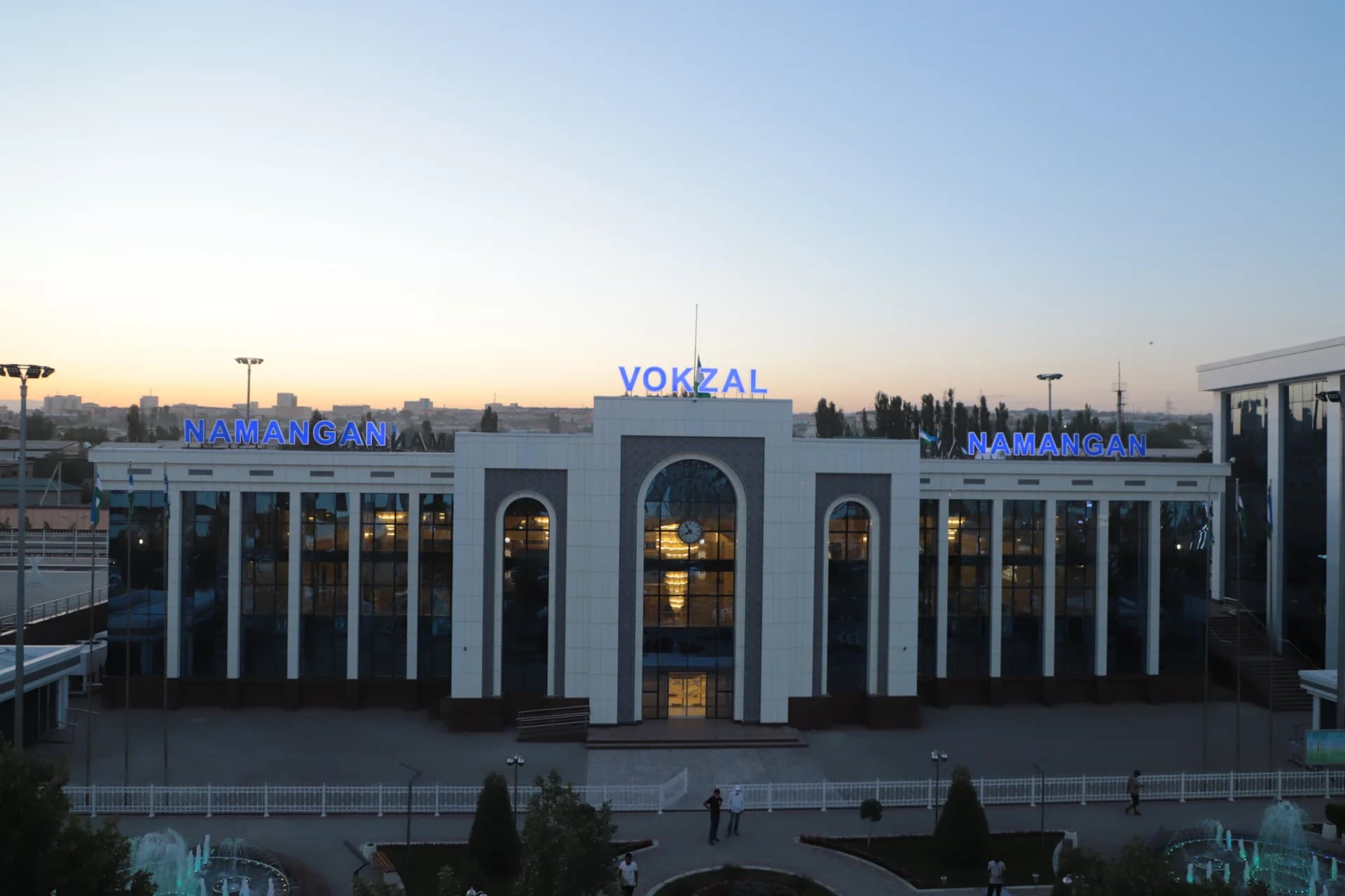Exterior view of a modern railway station building with illuminated signage