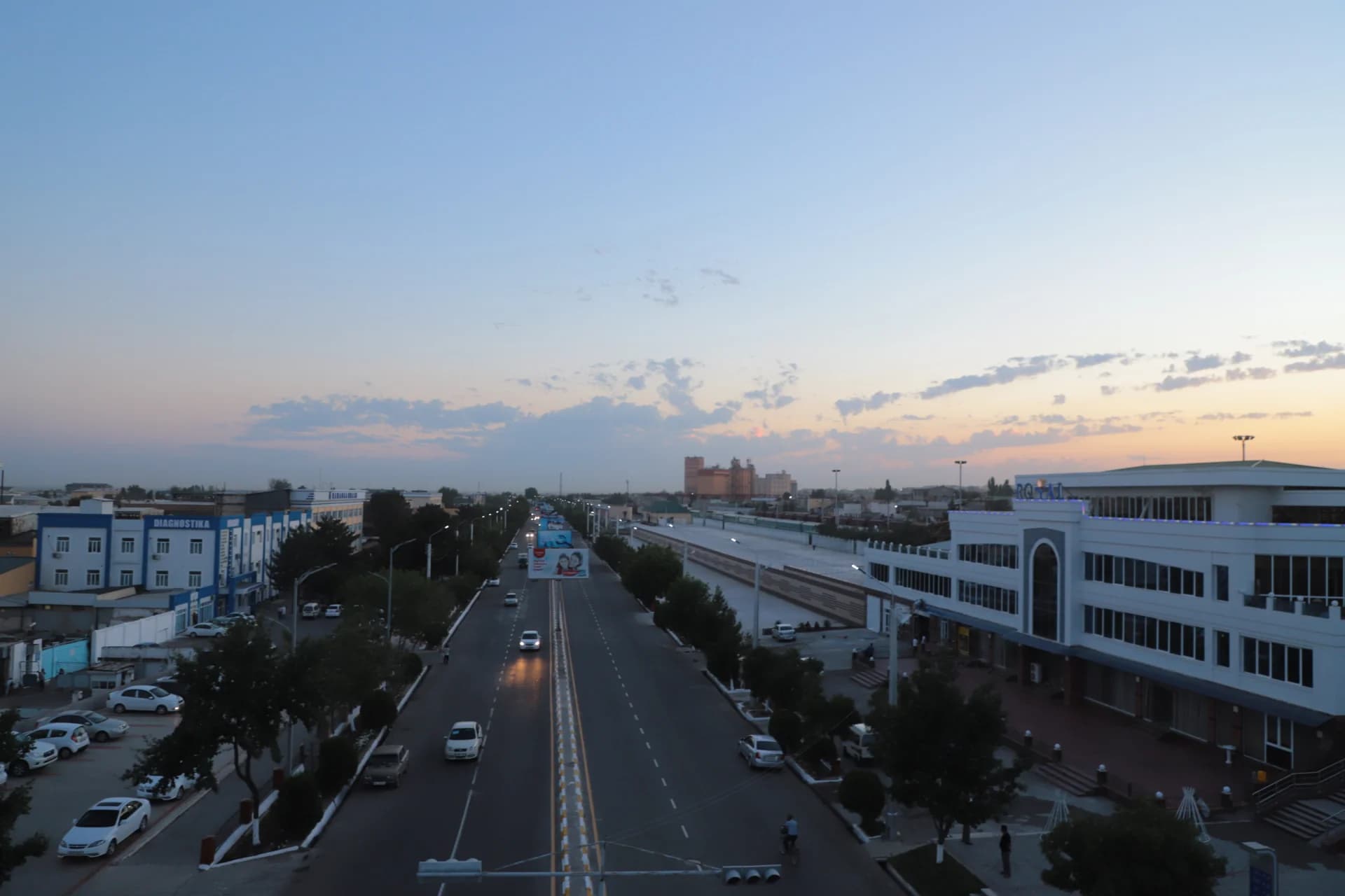 City street view with vehicular traffic and buildings under a dusk sky