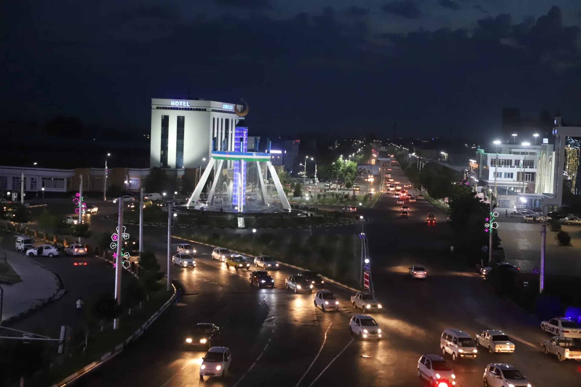 Night city street traffic and illuminated fountain monument