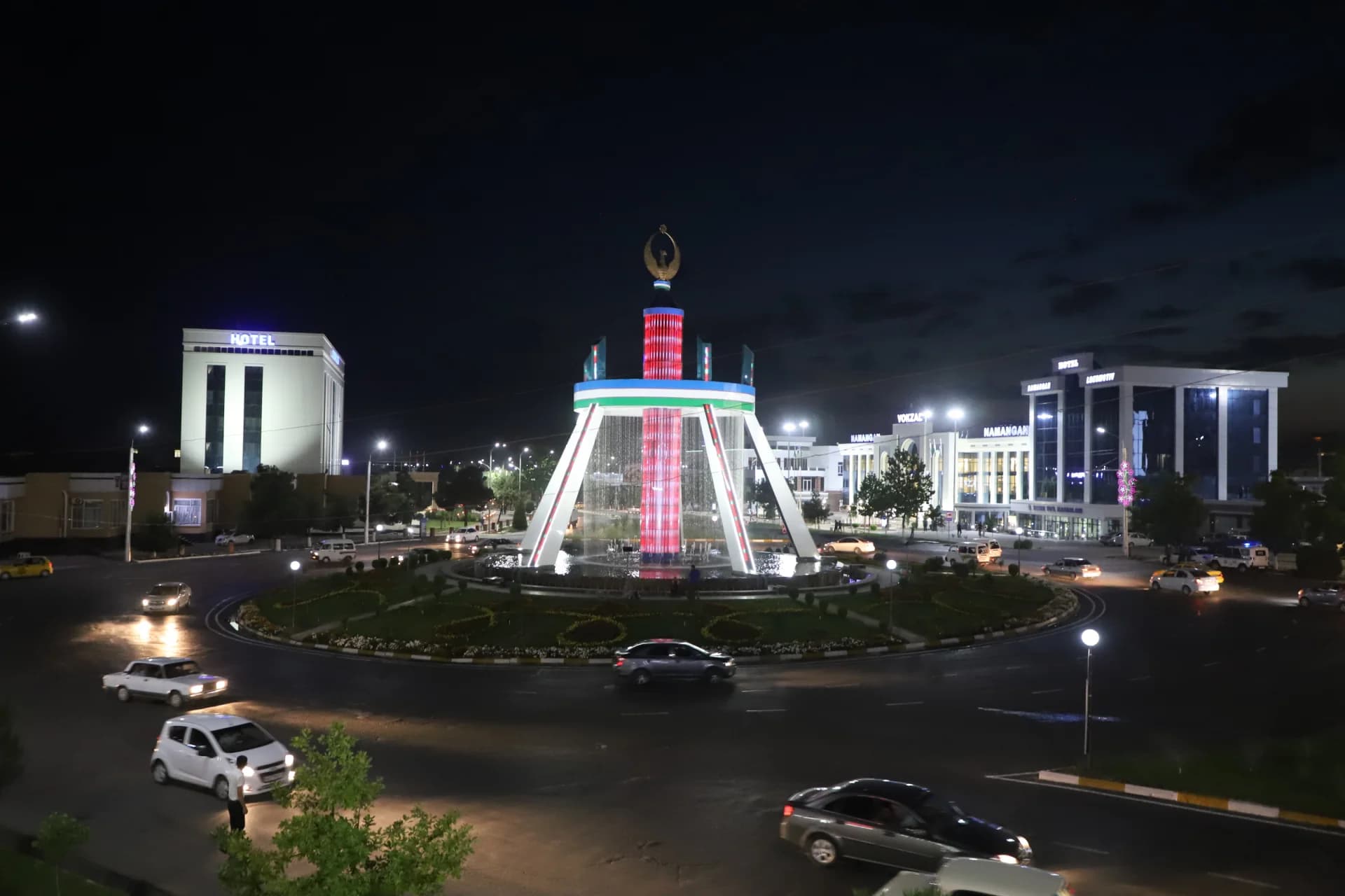 Illuminated city square with a central fountain at night