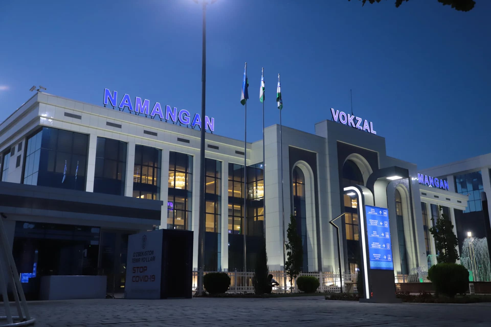 Illuminated exterior facade of Namangan railway station at dusk