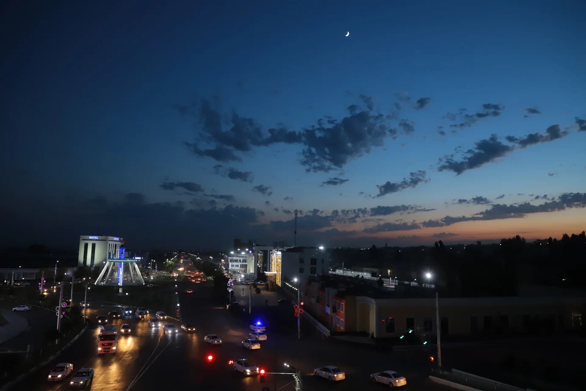 Night cityscape with illuminated streets and buildings under a dusk sky