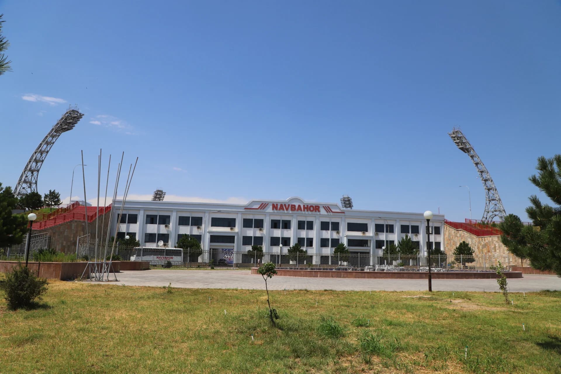 Exterior view of a modern sports stadium with large white building structure and lighting towers under a clear blue sky