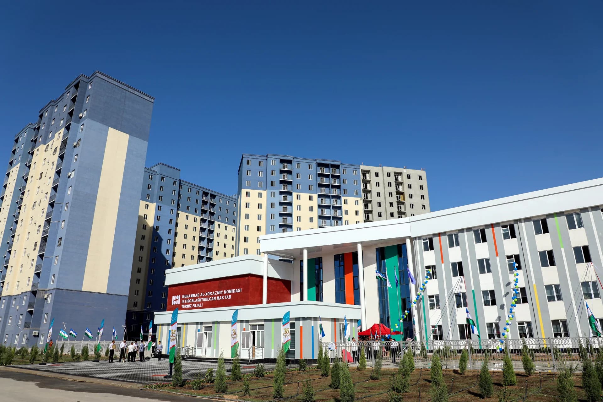 Multi-story apartment buildings and a school structure under a clear blue sky