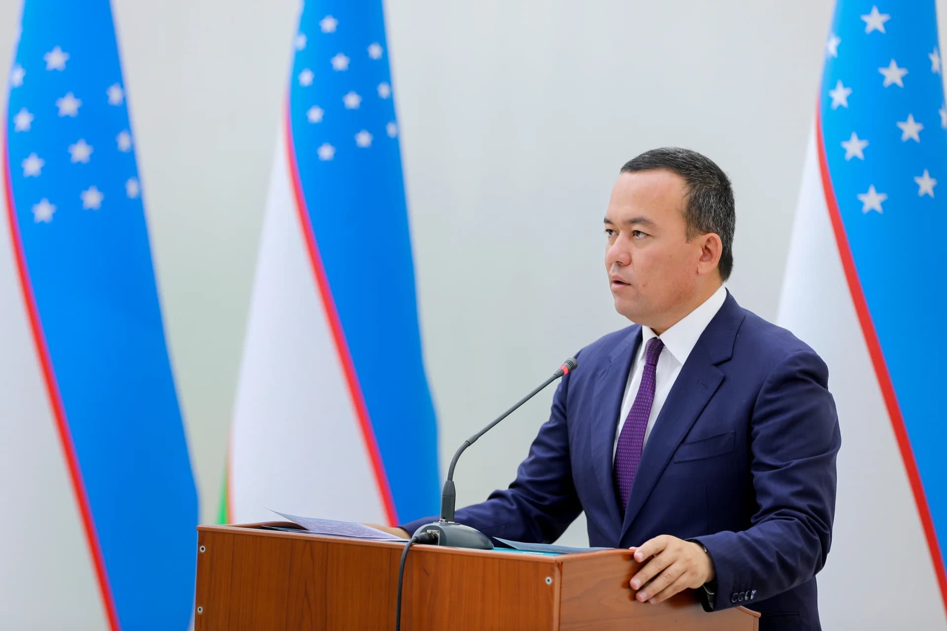 Man speaking at a podium in front of flags
