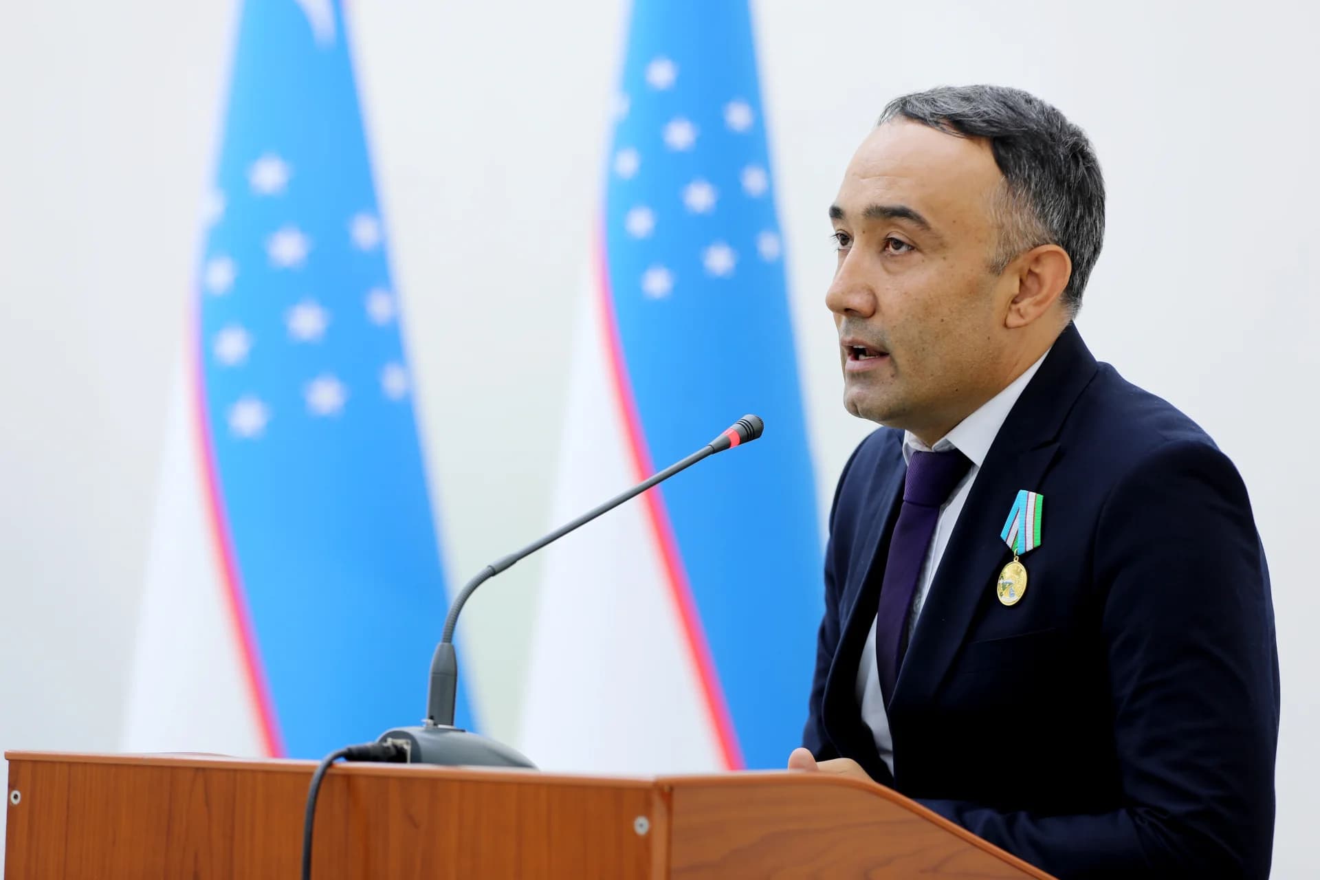 Person speaking at a podium with flags