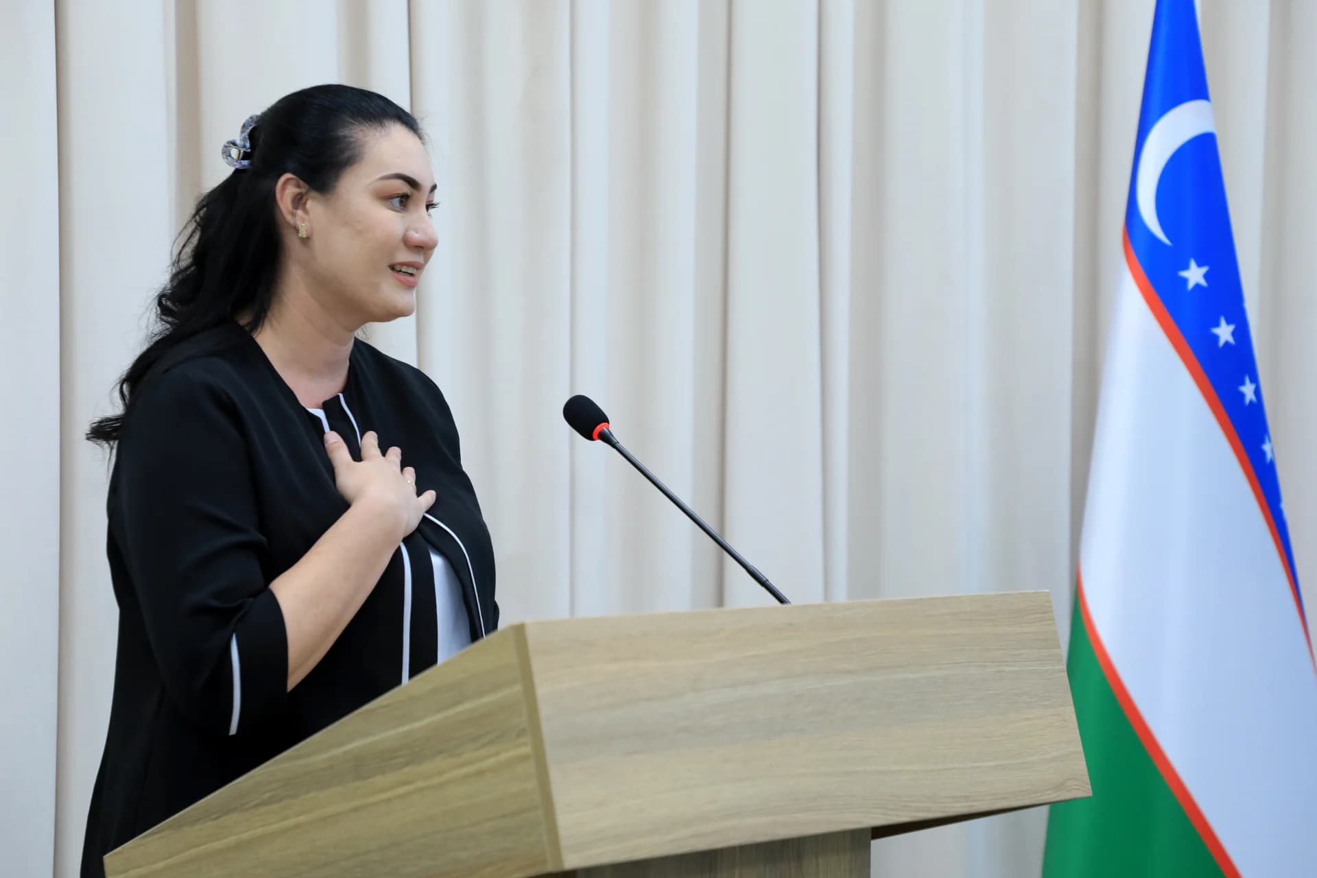 Woman speaking behind a podium next to a flag