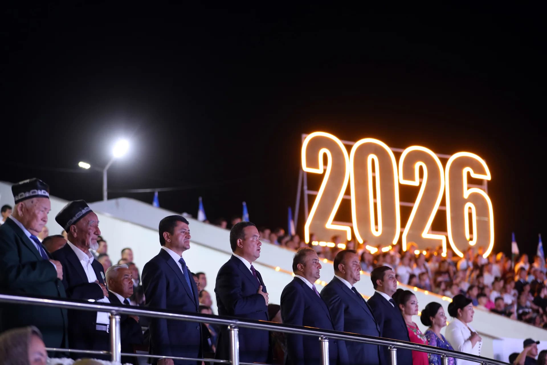 People gathered at an evening stadium event with an illuminated display