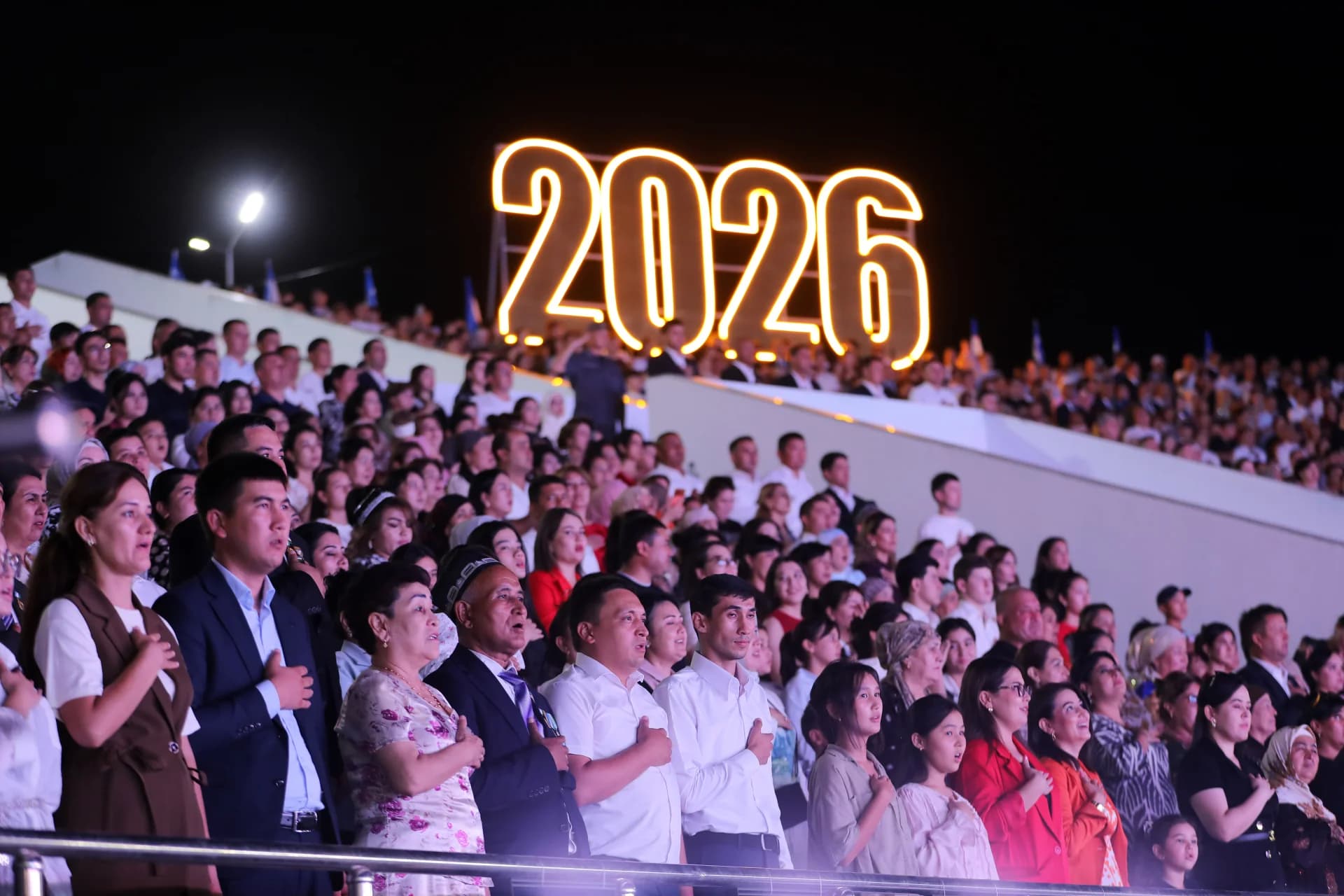 People gathered in a stadium with illuminated year sign at night