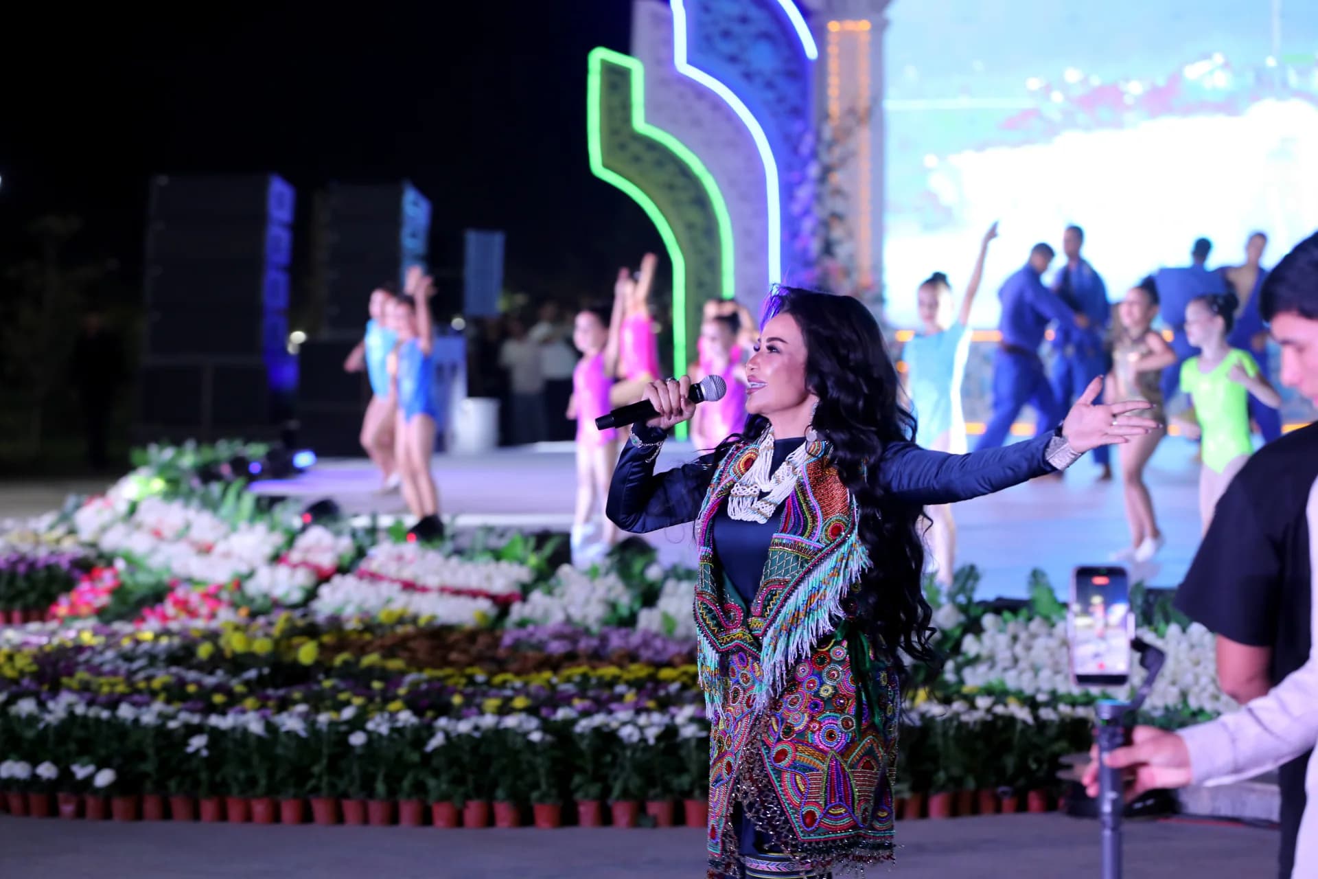 Performer singing on stage during an outdoor cultural event
