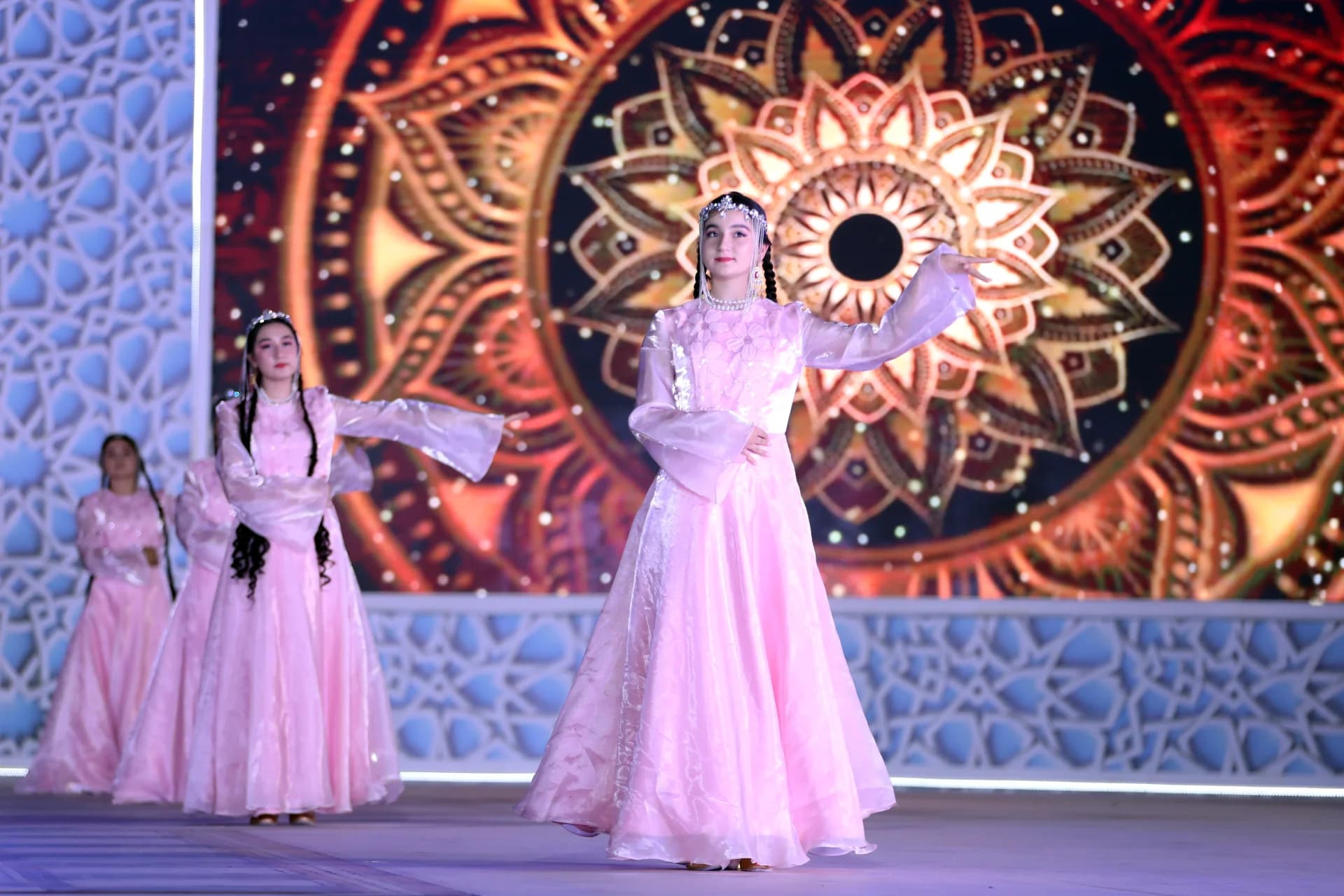 Performers in traditional pink dresses dancing on stage
