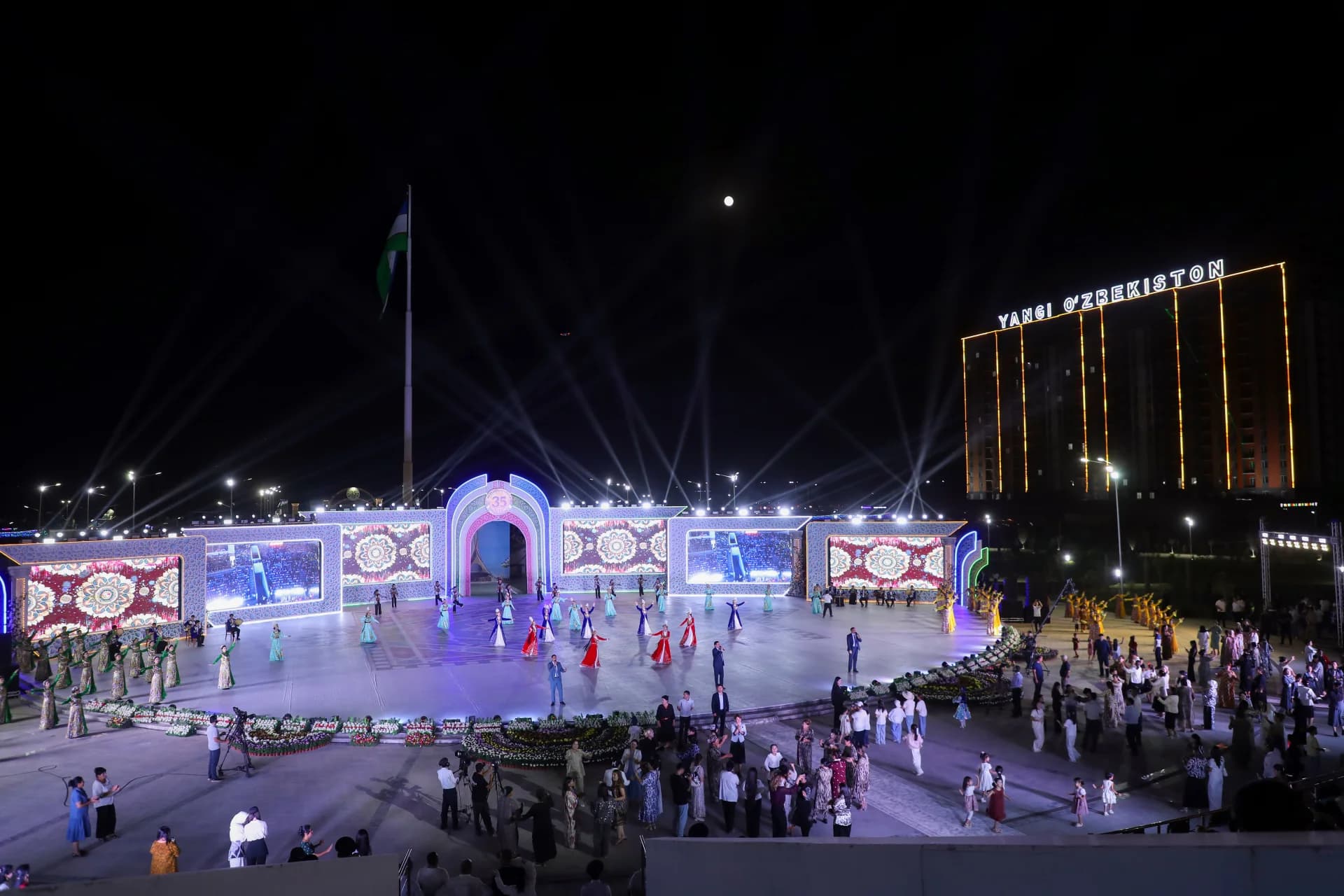 People gather for an evening outdoor public event with stage performances