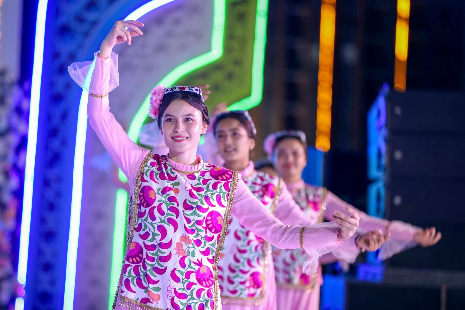 People perform a traditional dance in colorful costumes during an evening event
