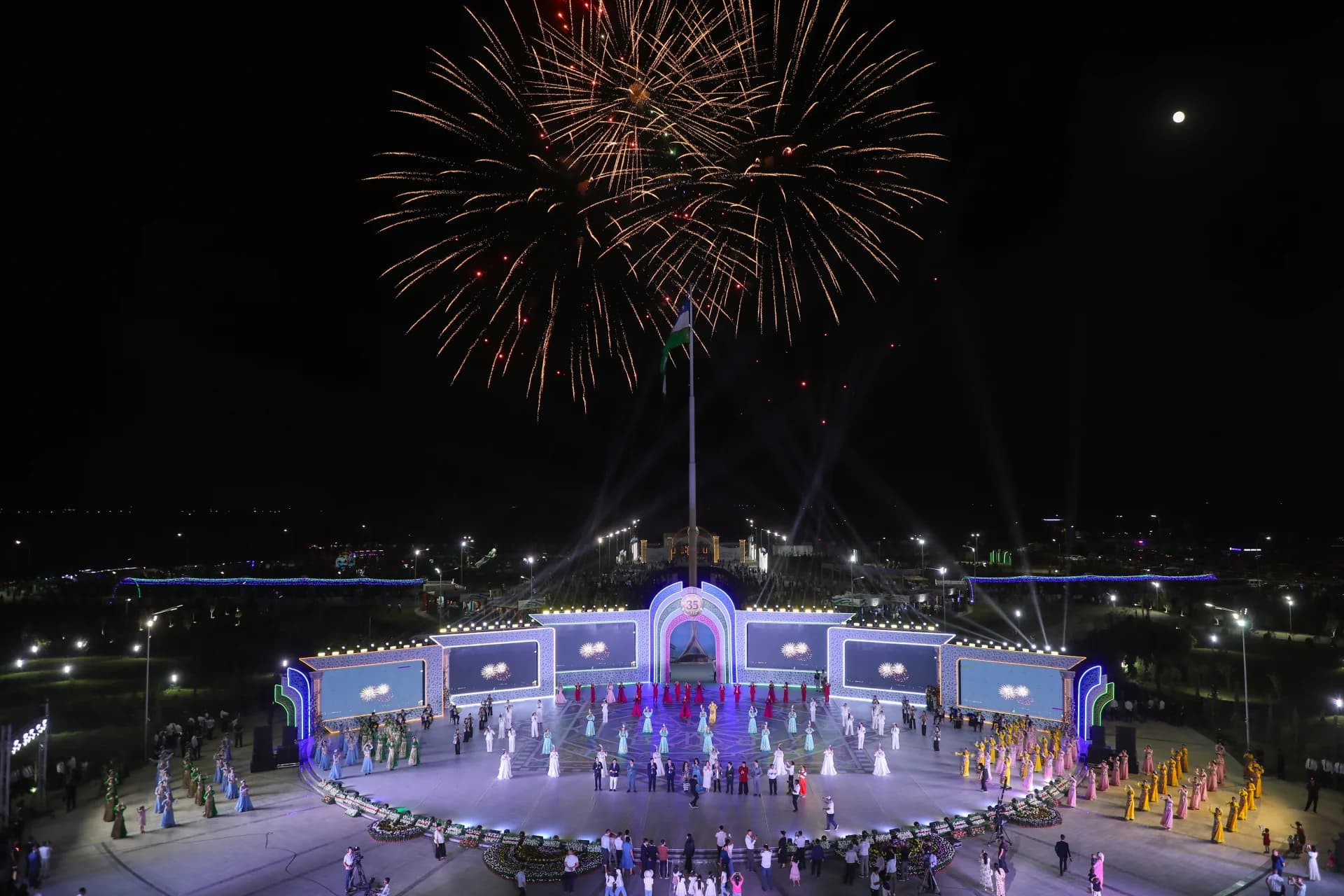 Fireworks display over an illuminated outdoor stage at night