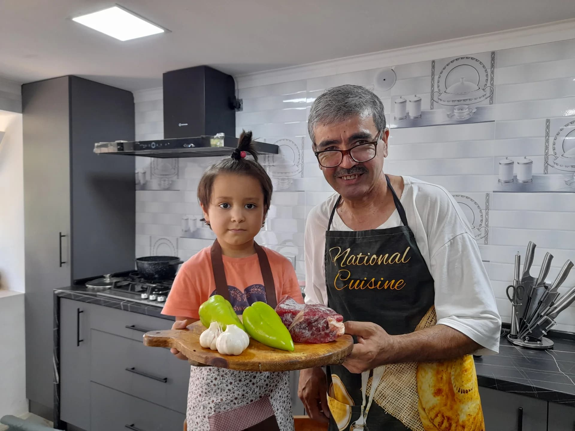 Люди, держащие деревянную разделочную доску с продуктами на кухне