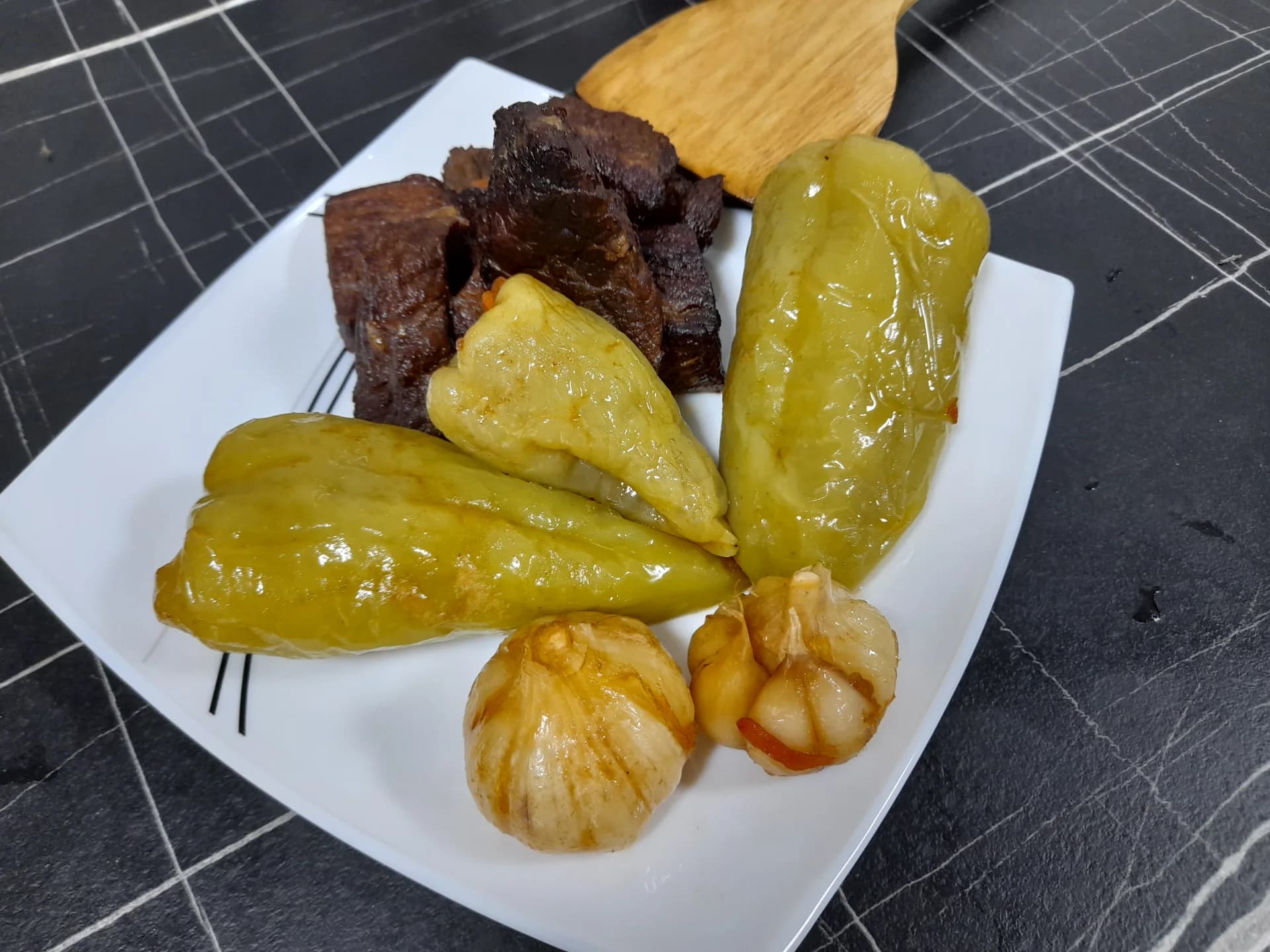 Фаршированный перец и мясо подаются на белой тарелке