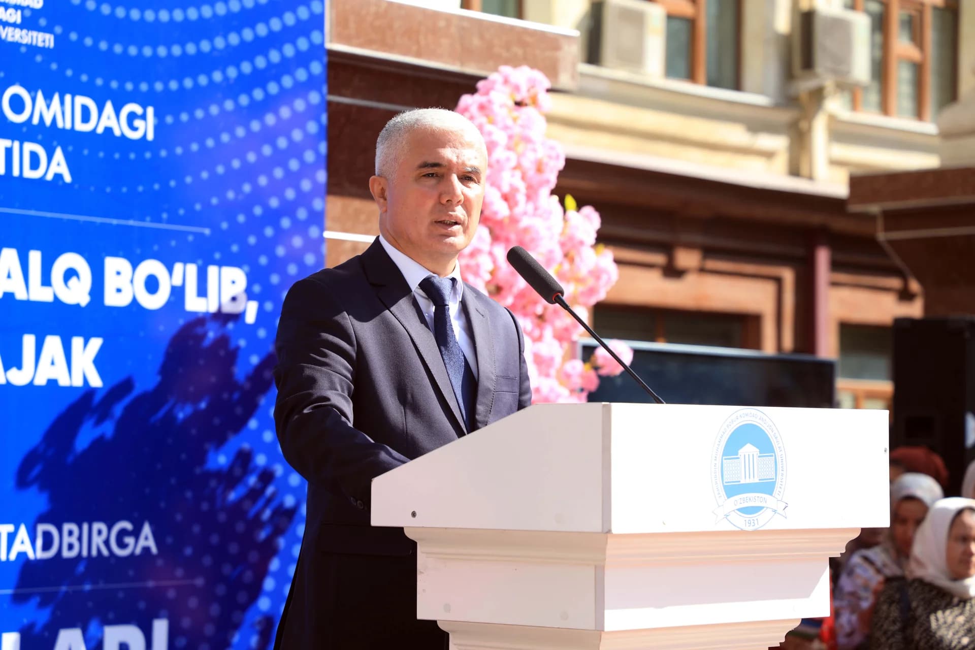 Мужчина, говорящий на трибуне на открытом воздухе