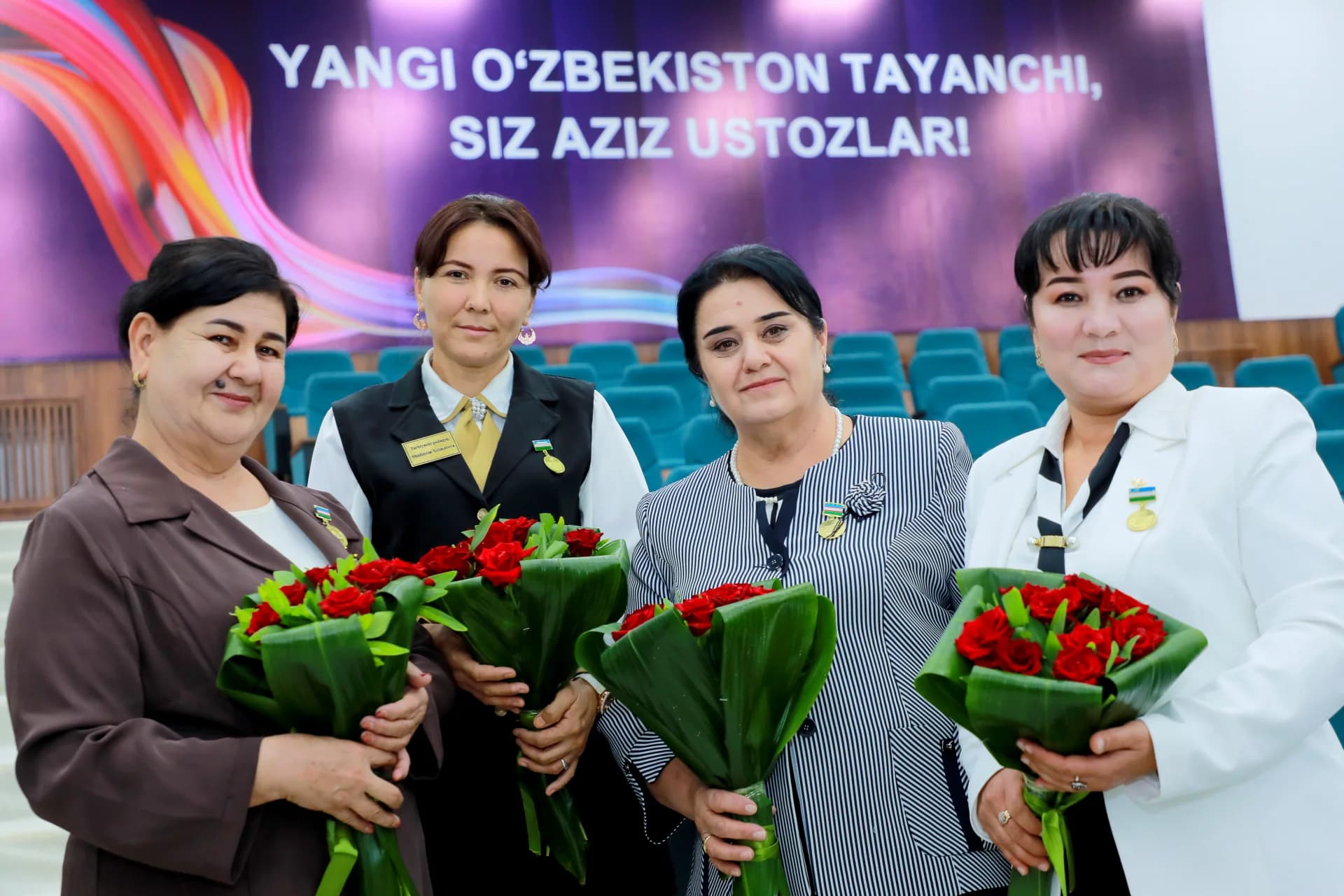 Four women holding bouquets of red roses indoors