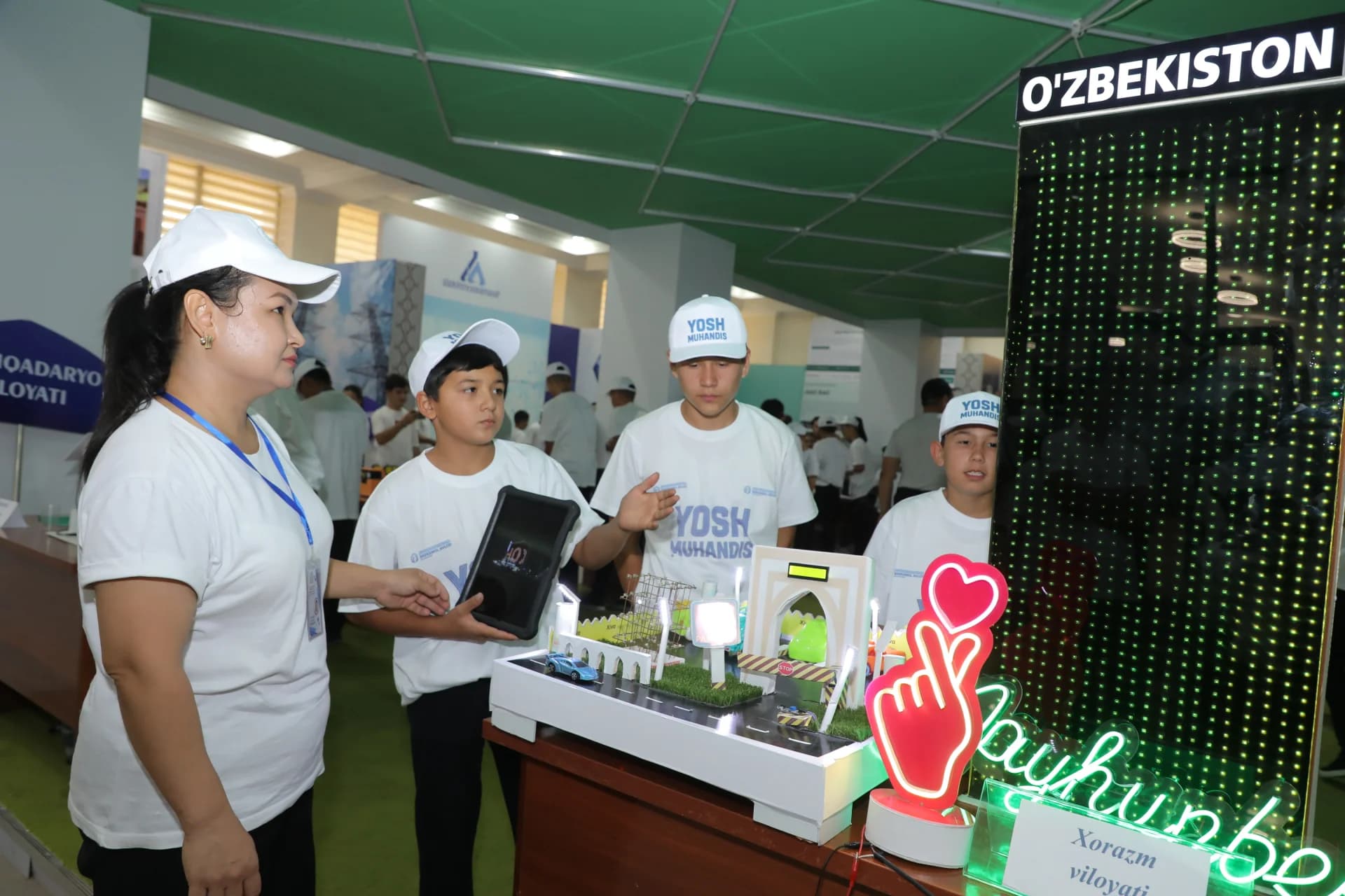 People examining a miniature model with electronic components and a digital display