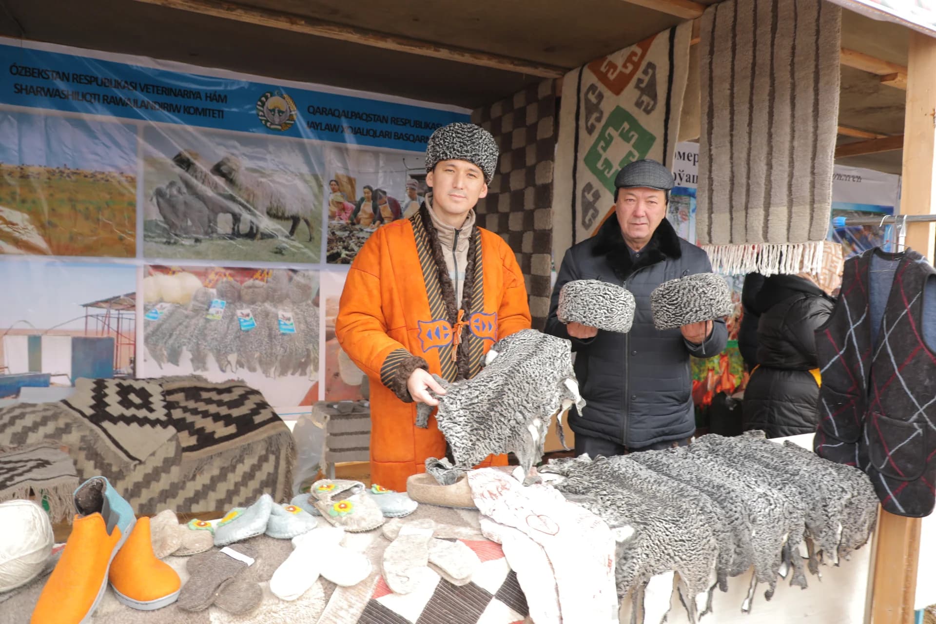 Men showcasing fur products and traditional clothing at a display stall