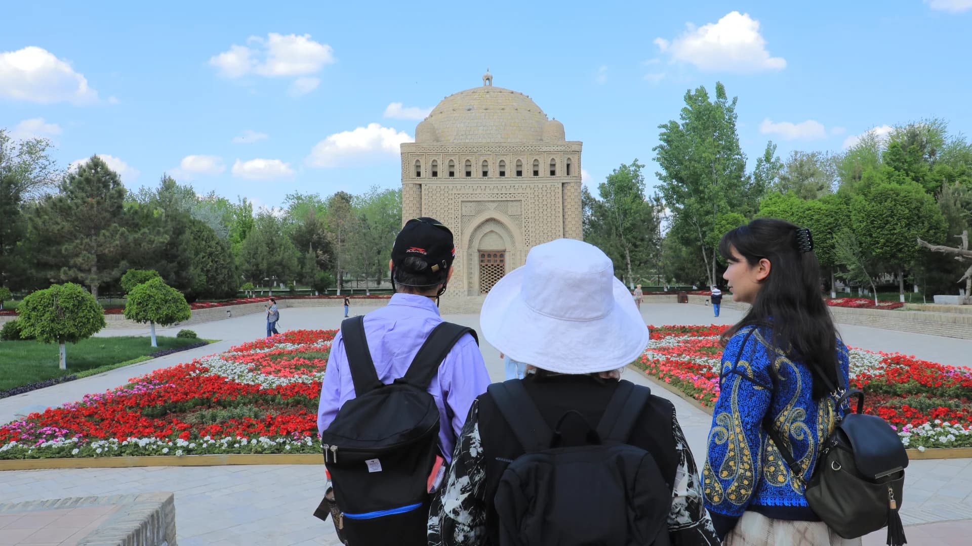 Tourists view a historic domed brick building in a park