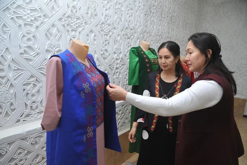 Women examine traditional embroidered clothing