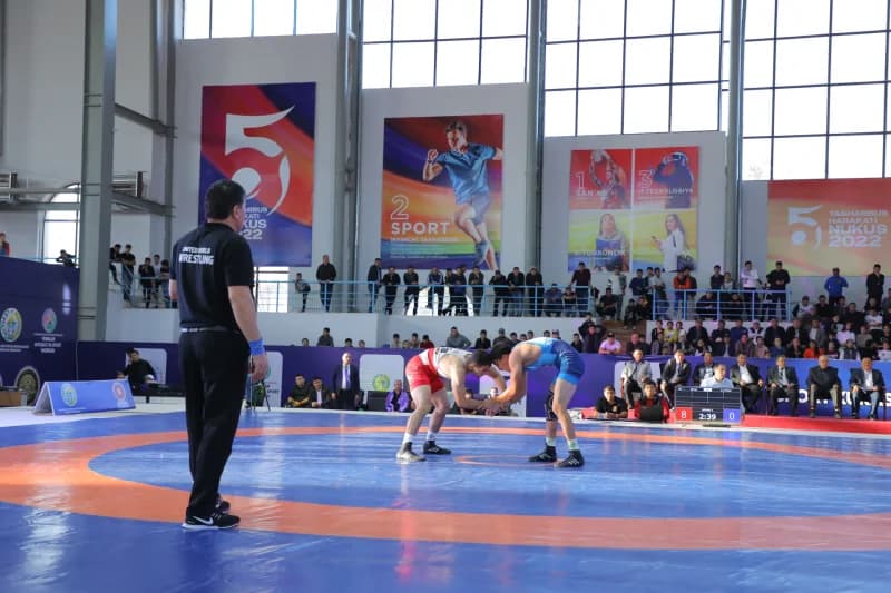Wrestlers compete on blue mat