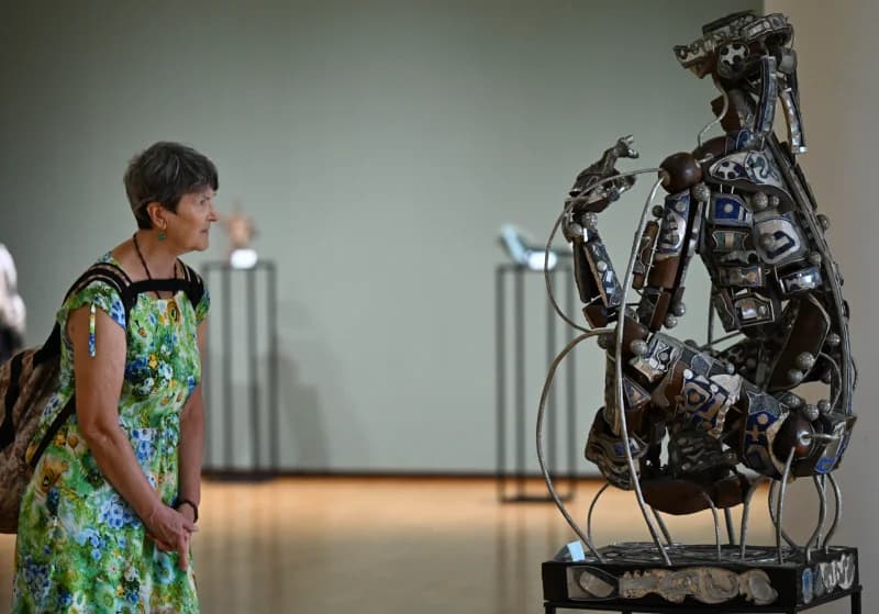 Visitor examining sculpture in museum gallery